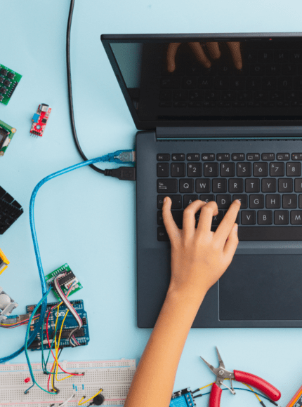 Child coding on a laptop with robotics components on the desk.