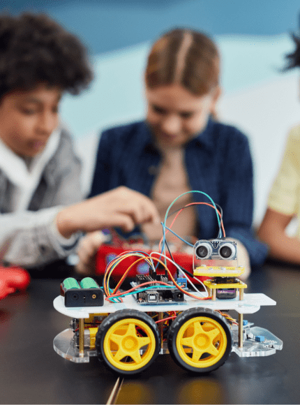 Three children working together on a robot in a STEM learning environment.